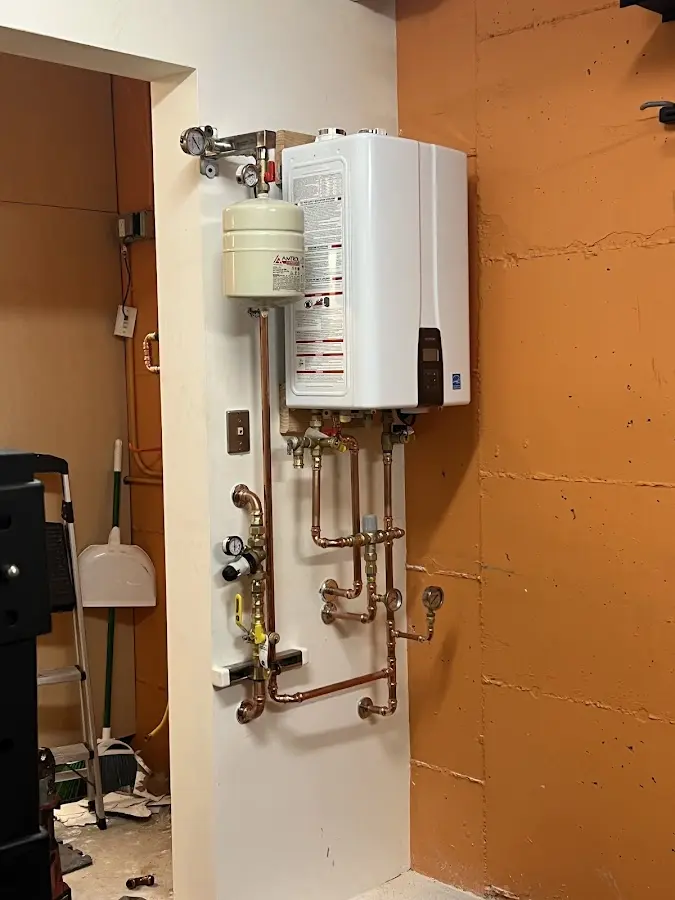 Plumbing technician inspecting water heater connections in Watertown